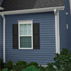 a blue house with black shutters and a white cat in the front yard area