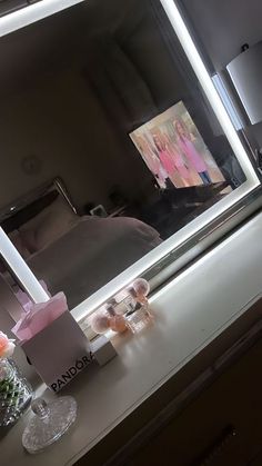 a bathroom vanity with a lighted mirror and pink flowers on the counter next to it