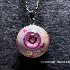 a pink eyeball with a heart in the center on a silver ball chain necklace