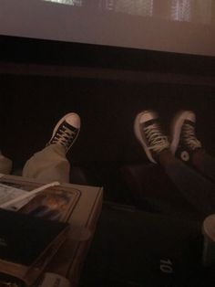 two people sitting in front of a projector screen with their feet up on the table