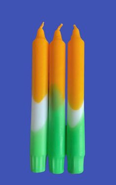 three green, white and orange candles on a blue background