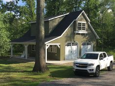 a white truck parked in front of a green house with two garages on each side