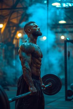 a man with tattoos on his chest and arms is holding a barbell in the gym