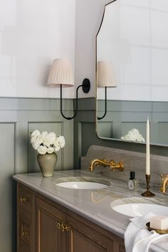 a bathroom with two sinks and a large mirror on the wall above it is decorated with white flowers