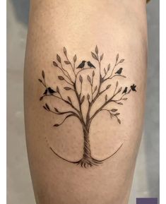 a small tree tattoo on the thigh with birds perched on it's branches and leaves