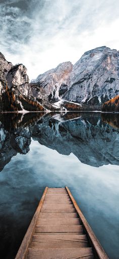 a wooden dock sitting on top of a lake surrounded by mountains