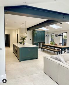 a large open kitchen and living room area with an island in the middle that is surrounded by white tile flooring