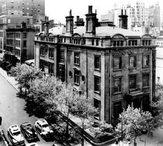 an old black and white photo of cars parked on the street in front of buildings