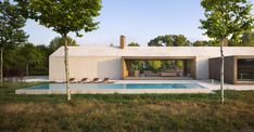 a house with a swimming pool in the middle of some grass and trees around it