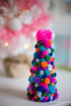 a small christmas tree made out of pom - poms sits on a table