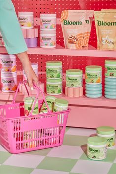 a person holding a pink shopping basket in front of shelves filled with different types of products