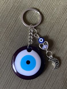 a blue and white evil eye keychain hanging from a metal ring on a table