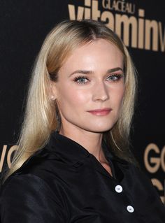 a woman with long blonde hair and blue eyeshadow wearing a black shirt at an event