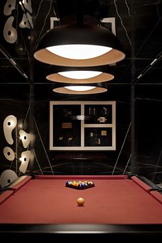 a red pool table sitting in front of a wall with pictures and lights on it