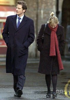 a man and woman walking down the street in winter clothes, one wearing a red scarf