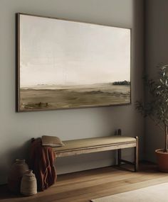 a painting hangs on the wall above a bench in a room with wooden floors and potted plants