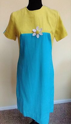 This gorgeous pencil silhouette dress is a linen feel material.  The cut and make of the dress is quality.  The colors are a vibrant blue and yellow and the daisy pin adds a 1960s touch.  It is too very classy and because the fabric is natural it would be comfortable to wear.  It closes with a zipper up the back.  It has some nobs in the fabric, but I told that this is natural and not from wear.   The dress was most likely worn by my elderly neighbor when she worked in the bank.  It's been stored for a long time and washed and steamed and ready for a new home. Dress is a small and the measurements are: Neck 6.25" Shoulder to shoulder 14" Armpit to armpit 17.5 Waist 16" Hips 17.5 Length  38" There is no stretch in the fabric so measure carefully for a great fit! Yellow Linen Short Sleeve Dress For Summer, Yellow Fitted Short Sleeve Dress, Fitted Blue Linen Dress, Fitted Yellow Linen Dress, Yellow Fitted Linen Dress, Fitted Blue Linen Dress For Spring, Blue Short Sleeve Linen Dress For Summer, Blue Fitted Knee-length Linen Dress, 1950s Shirtwaist Dress