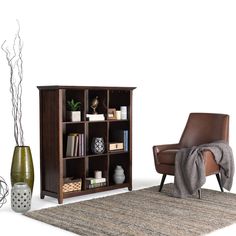 a living room with a chair, bookcase and vases on the floor in front of it