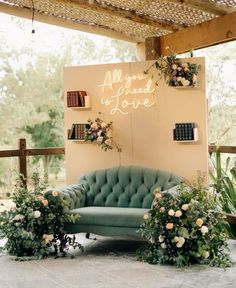 a green couch sitting in front of a wall with flowers and greenery on it