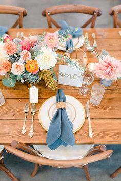 a wooden table topped with plates and flowers