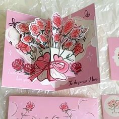 two cards with flowers and hearts on them, one is folded in the shape of a heart