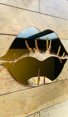 a mirror that is on the side of a wooden wall with a gold leaf design