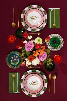 the table is set with plates, silverware and flowers