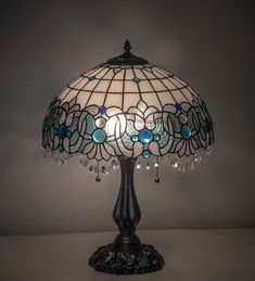 a stained glass table lamp with blue and white flowers on the bottom, surrounded by crystal beads