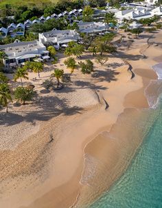 an aerial view of a beach with houses in the background and water at the bottom