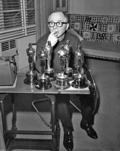 an older man sitting at a table with trophies