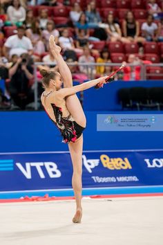 a woman is doing an acrobatic move in front of a crowd