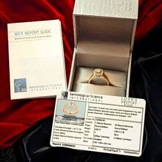 an engagement ring sits in a box on a red velvet surface next to it's owner's identification card