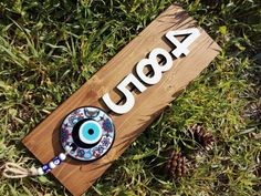 a wooden sign sitting on top of a lush green field next to a pine cone