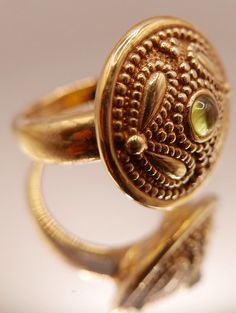 Vintage 14 carat gold Etruscan Revival ring with bezel set peridot gemstone and ornate granulation on medallion style head. Beautiful artisan piece with exquisite attention to detail including etching on underside of head.  Stamped 14K Excellent vintage condition Ring size: US 7 Head diameter: 2.2 cm / 0.7 inch Weight: 2.46 grams ☞ Please view my shipping and sales policies and ✎ Contact me with questions prior to purchase...all sales are final. http://www.etsy.com/shop/Andeebird/policy Elegant Domed Jewelry With Bezel Setting, Gold Cabochon Jewelry For May Birthstone, Gold Byzantine Jewelry With Cabochon, Byzantine Gold Cabochon Jewelry, Byzantine Gold Jewelry With Cabochon, Ornate Gold Filigree Ring, Byzantine Round Hallmarked Jewelry, Gold Byzantine Jewelry With Bezel Setting, Elegant Brass Rings With Cabochon