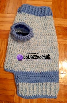 a blue and white crocheted bag with a hole in the middle on a wooden floor