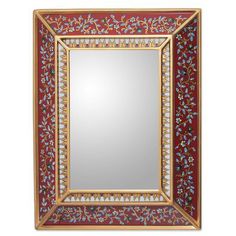 a mirror hanging on the wall with a red and gold border around it's edge