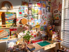 a desk with lots of children's artwork on the wall and shelves above it