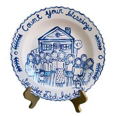 a blue and white plate with an image of people standing in front of a house