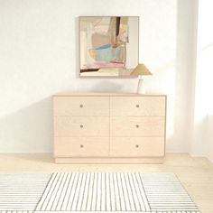 a room with a dresser, lamp and painting on the wall