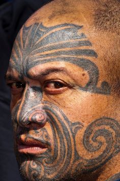 a man with tattoos on his face and neck