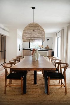 a dining room table with chairs and a vase on top of it in front of a window