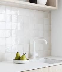 two pears in a white bowl on a kitchen counter top next to a faucet