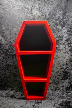 a red shelf sitting on top of a black counter next to a gray wall and floor