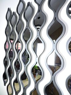 a mirror that is reflecting the reflection of people in it's reflection, as well as an abstract wave design