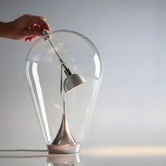 a person is lighting a lamp in a glass vase