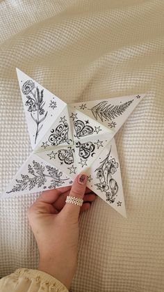 someone is holding an origami star with designs on it and pointing to the side