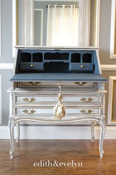 an old dresser has been painted white and blue with gold trimming on the drawers