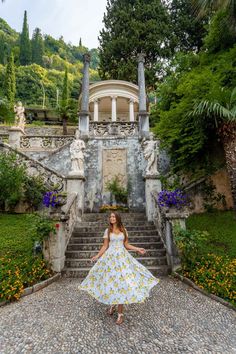 a woman in a white dress standing on the steps leading to a building with columns