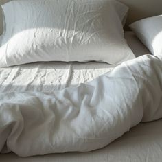 an unmade bed with white sheets and pillows