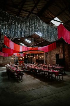 a large room with tables and chairs covered in pink tablecloths hanging from the ceiling